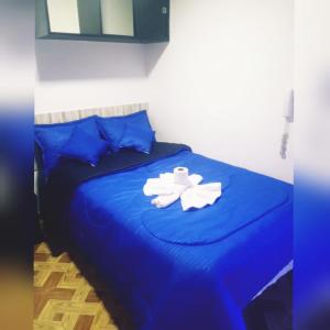 Un dormitorio con una cama azul con toallas. en Hotel Villa Real en Bogotá