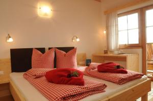 Gerlhof في Obernussdorf: غرفة نوم بسريرين ومخدات حمراء
