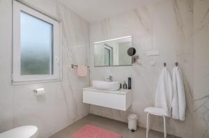 biała łazienka z umywalką i lustrem w obiekcie Modern Apartments Elle Malinska w mieście Vantačići