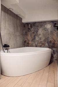 uma banheira branca na casa de banho com uma parede em Hotel Alf em Borovany