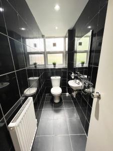 een zwart-witte badkamer met een toilet en een wastafel bij Large apt close to central LDN in Londen