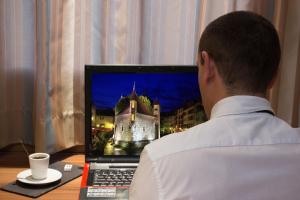 a man sitting at a table with a laptop computer at Hotel Novel Restaurant La Mamma in Annecy