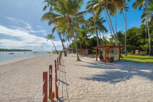 a sandy beach with palm trees and a wooden fence at Pousada Sitio da Prainha in Praia dos Carneiros