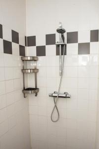 um chuveiro numa casa de banho com azulejos pretos e brancos em De Donksehoeve em Liempde