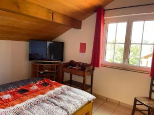 1 dormitorio con 1 cama y TV de pantalla plana en Chambres d'hôtes en Les Genevez