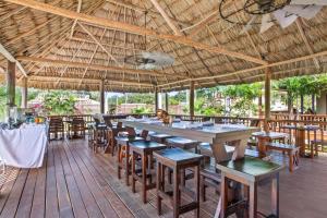 un restaurante con mesas y sillas y una sombrilla grande en Sirenian Bay Resort -Villas & All Inclusive Bungalows en Placencia Village