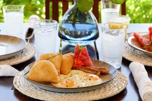 a table with a plate of breakfast food on it at Sirenian Bay Resort -Villas & All Inclusive Bungalows in Placencia