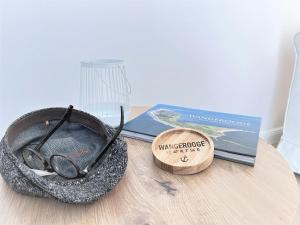 une table avec une paire de lunettes et un livre dans l'établissement Haus Alexandra - Ferienwohnung Dat Büdche, à Wangerooge