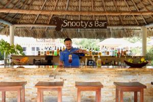 Sirenian Bay Resort -Villas & All Inclusive Bungalows في بلاسينسيا فيليدج: رجل يقف خلف البار مع الشراب