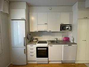 a kitchen with white cabinets and a white refrigerator at River in Rovaniemi