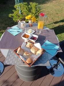 Saint-Martin-lez-TatinghemにあるChambres d'Hôtes Les Mésangesのピクニックテーブル(パンとオレンジジュースのトレイ付)