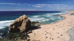 a beach with a large rock and a group of people at Casa da Formosa in Silveira