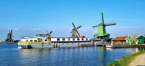 阿姆斯特丹Unique Hotelboat botel Lena Maria的船停靠在码头上,船身有风车