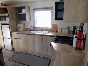 a kitchen with wooden cabinets and a stove top oven at Camelot Holiday Park, Longtown, Tranquility 21 Coworth in Carlisle