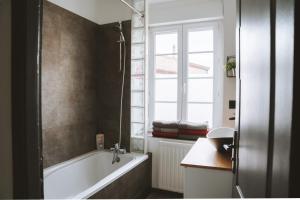 uma casa de banho com uma banheira e uma janela em Appartement meublé 60m2 Le Drômardèchois ARDÈCHE -GESTLOC- em Tournon-sur-Rhône