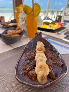 un plato de comida con plátanos y nueces en una mesa en Equalia Rose hotel en Jambiani