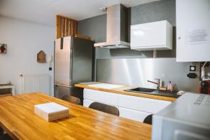 a kitchen with a wooden table and a refrigerator at Le DrômArdèchois - Gîte meublé Ardèche - WIFI Parking - Écolodgîte Drôme ardèche in Tournon-sur-Rhône