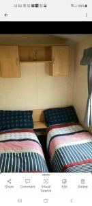two beds sitting next to each other in a room at TM18 - 3 Bedroom Mobile Home Golden Palms Resort TV`s in Every Room Decking Indoor Heated Pool Entertainment complex & Close To Beaches PASSES NOT INCLUDED in Skegness