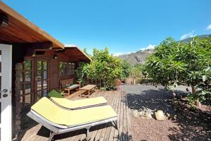 a deck with two lounge chairs and a house at Cottage Hibiscus among Avocados in La Orotava