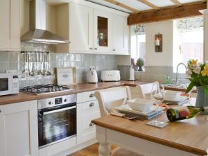 uma cozinha com armários brancos e uma mesa de madeira em West Wood Hideaway em Middleton