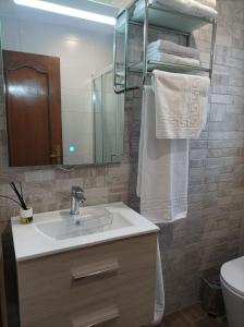 a bathroom with a sink and a mirror and towels at Balcón del Cardenal in Baeza