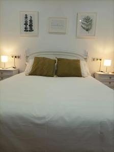 a bedroom with a large white bed with two lamps at Balcón del Cardenal in Baeza