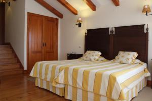 a bedroom with a large bed with yellow and white stripes at Casa de Campo Sao Rafael - Turismo Rural in Óbidos