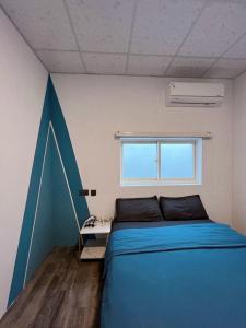 a bedroom with a blue bed and a window at 私家潛水旅宿 in Green Island