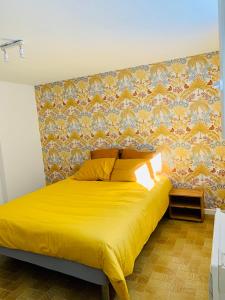 1 dormitorio con cama amarilla y pared en Appartement quartier calme en Mende
