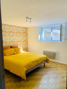 1 dormitorio con cama amarilla y ventana azul en Appartement quartier calme en Mende