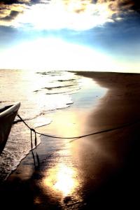 a boat sitting on a beach with the ocean at Sabalo Lodge Tours and Cabins in Sierpe