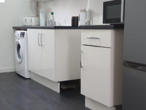 a white kitchen with a washing machine and a microwave at Blackwood Residence in Accrington