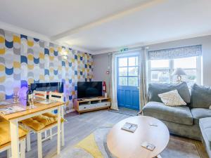 a living room with a couch and a tv at Awel Y Mor Sea Breeze in Cemaes Bay