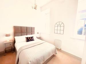 a white bedroom with a large bed and a window at Great Glen Townhouse Inverness in Inverness