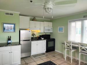  La cuisine est équipée de placards blancs et d'un réfrigérateur. dans l'établissement Sandpeddler Inn and Suites, à Wrightsville Beach
