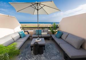 un patio con sofá y sombrilla y la playa en Mar Azul Fuerteventura, en Morro del Jable