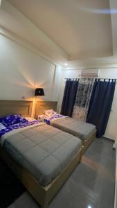 a bedroom with two beds and blue curtains at The One in Yaoundé