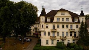 ein großes weißes Gebäude mit einem Dach in der Unterkunft Residenz am Kurpark - Ferienwohnungen in zentraler Lage I Privatparkplatz in Bad Rothenfelde