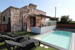 - une piscine avec des chaises et une maison dans l'établissement Il borgodellequerce CASA ULIVI PISCINA PRIVATA, à Martina Franca