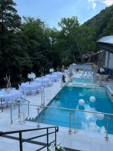 una piscina con mesas y sillas blancas en Hotel Holiday Maria, en Băile Herculane