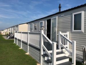 a mobile home with a porch and a white railing at AMETHYST 25 in Whitstable