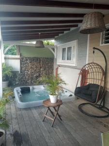 a hot tub on a patio with a chair at Une pause s'impose au Vauclin avec votre jacuzzi privatif pour 3 nuits minimum in Le Vauclin