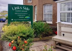 a sign for a guest house in front of a building at Links Side Guest House in Bude