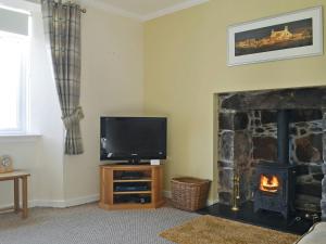 a living room with a television and a fireplace at Sunnybank Cottage in Inveralligin