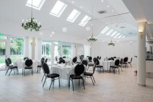 a banquet hall with white tables and chairs and windows at Landhotel Classhof in Willich