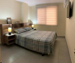 1 dormitorio con 1 cama con 2 lámparas y una ventana en Garzota Suites Gardens, en Guayaquil