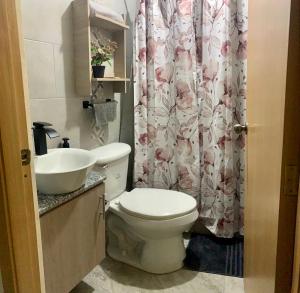 a bathroom with a toilet and a sink and a shower curtain at Garzota Suites Gardens in Guayaquil