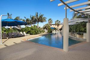 una piscina con sillas y una sombrilla en un complejo en Blue C Coolangatta, en Gold Coast