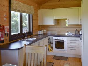 a kitchen with white cabinets and a sink and a stove at Dalch - Uk12538 in Witheridge