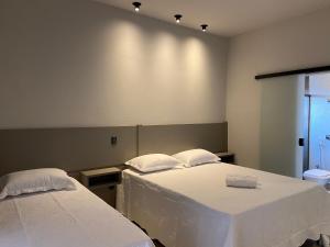 サン・ジョアン・バチスタ・ド・グローリアにあるPousada Pôr do Solの白いシーツが備わるベッド2台が備わる客室です。